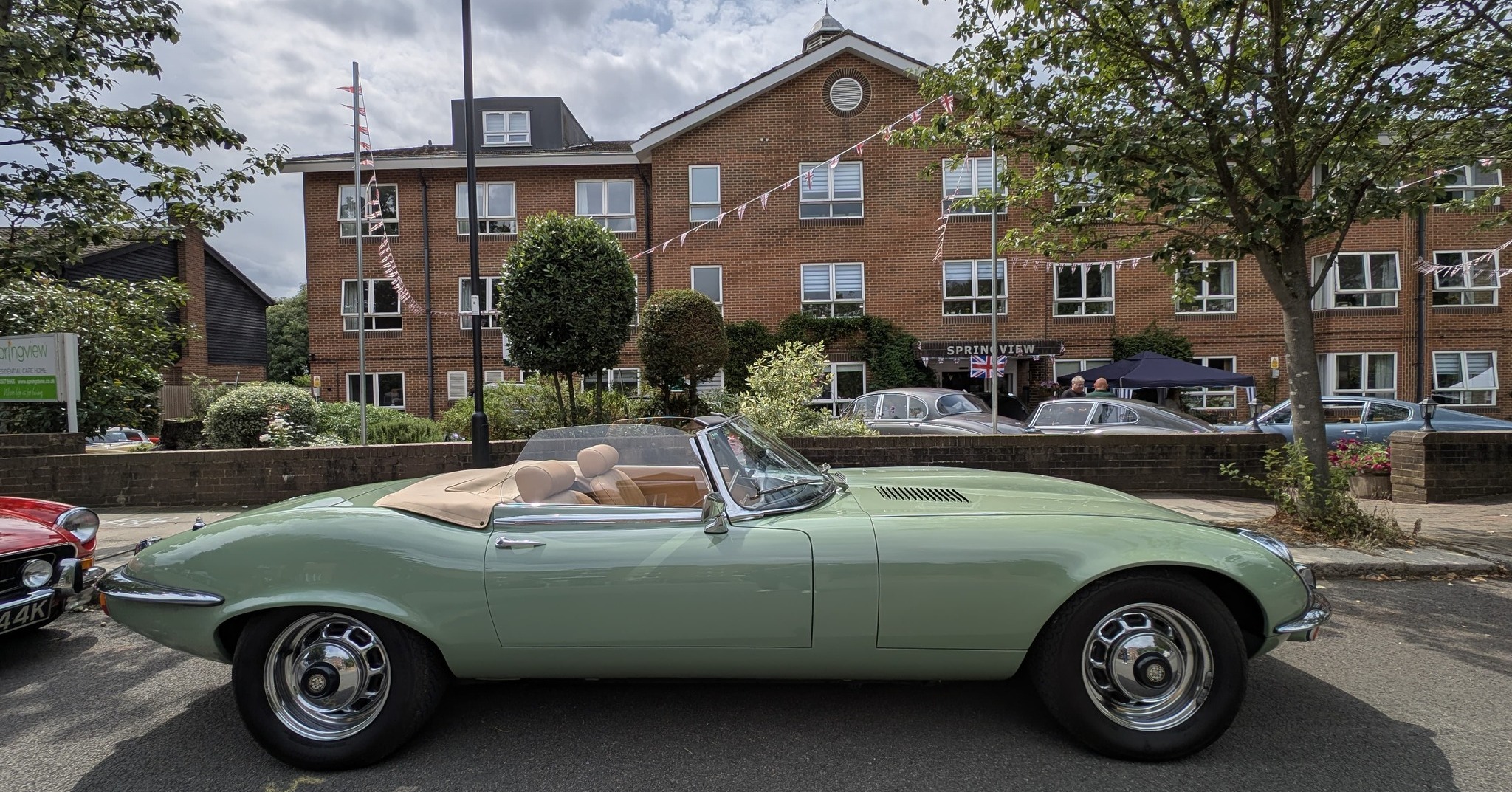 Light green classic Jaguar convertible on display outside Springview Care Home in Enfield, with residents and families enjoying the Summer Festival.