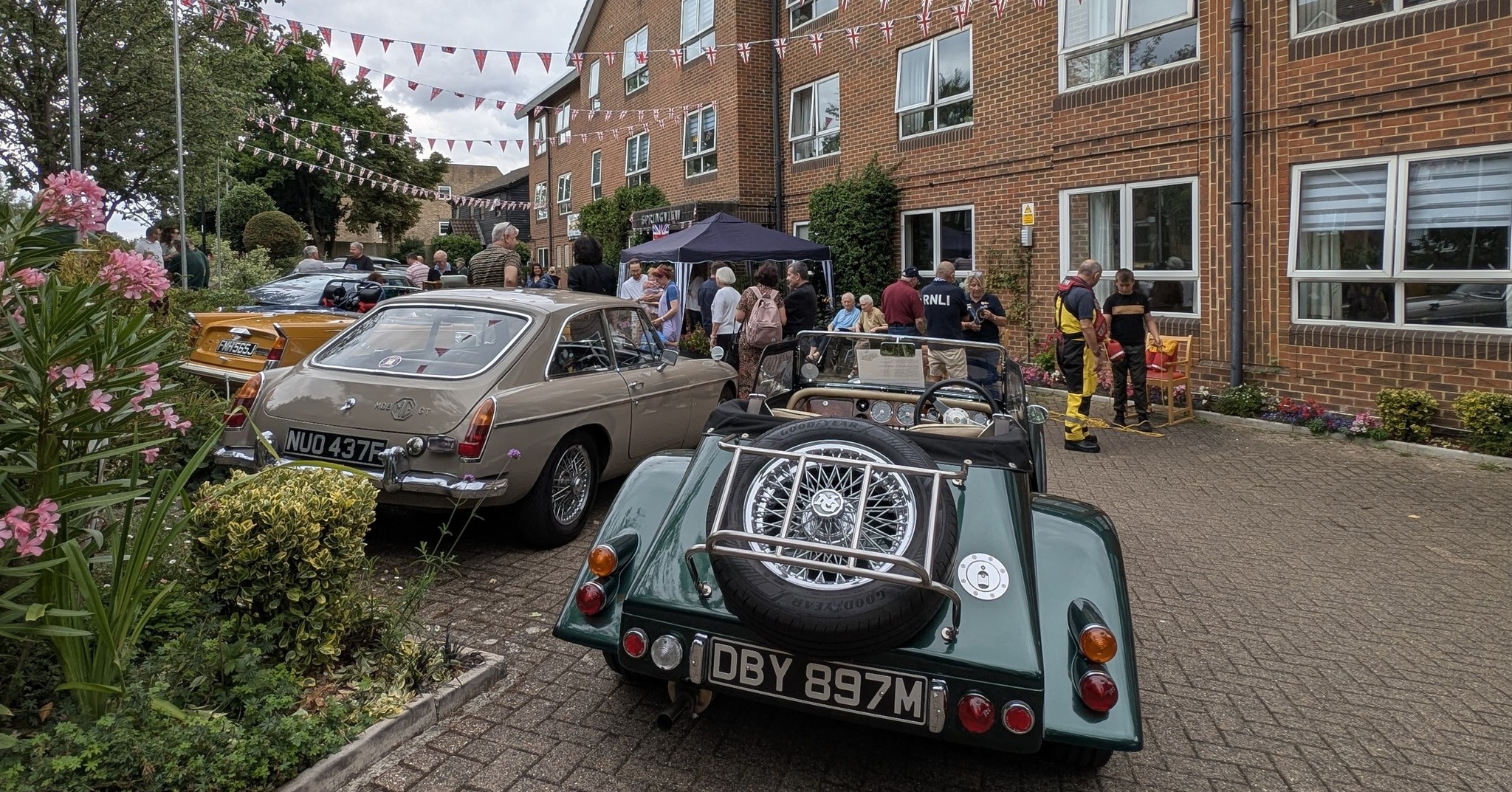 Green vintage MG with rear-mounted spare wheel among the classic cars at Springview Care Home Summer Festival in Enfield.