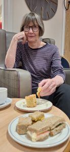 Care home resident smiling while tasting sandwiches during National Sandwich Day in North London.