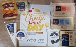 Selection of British cheeses arranged around National Cheese Lovers Day sign at Spring Lane Care Home Muswell Hill.