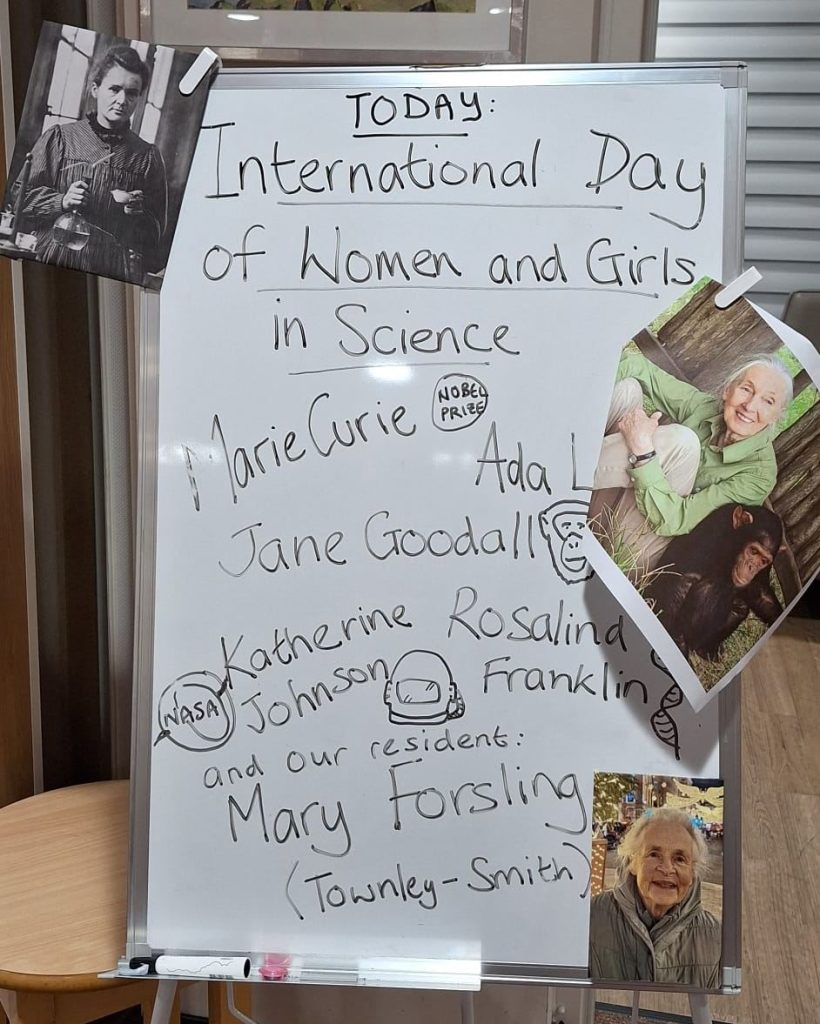 Whiteboard displaying International Women and Girls in Science Day with notable scientists at Spring Lane Care Home