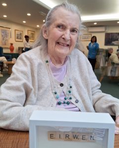 Resident holding a personalised Scrabble name display created during a word-themed activity at Spring Grove Care Home.