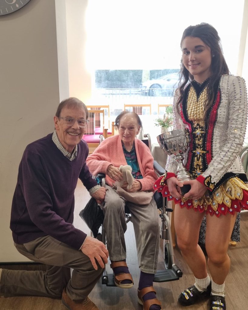 Resident and family enjoying meeting an Irish dancer during Springdene's St Patrick's Day event.