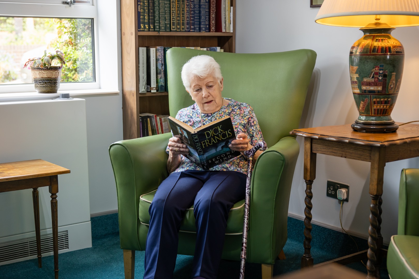 Resident relaxing with a book in a comfortable lounge at Springview Care Home in Enfield, North London