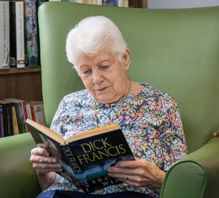 Springdene resident relaxing with a book in a comfortable reading area