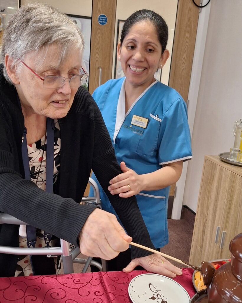 Springdene care team member supporting a resident to enjoy the chocolate fountain
